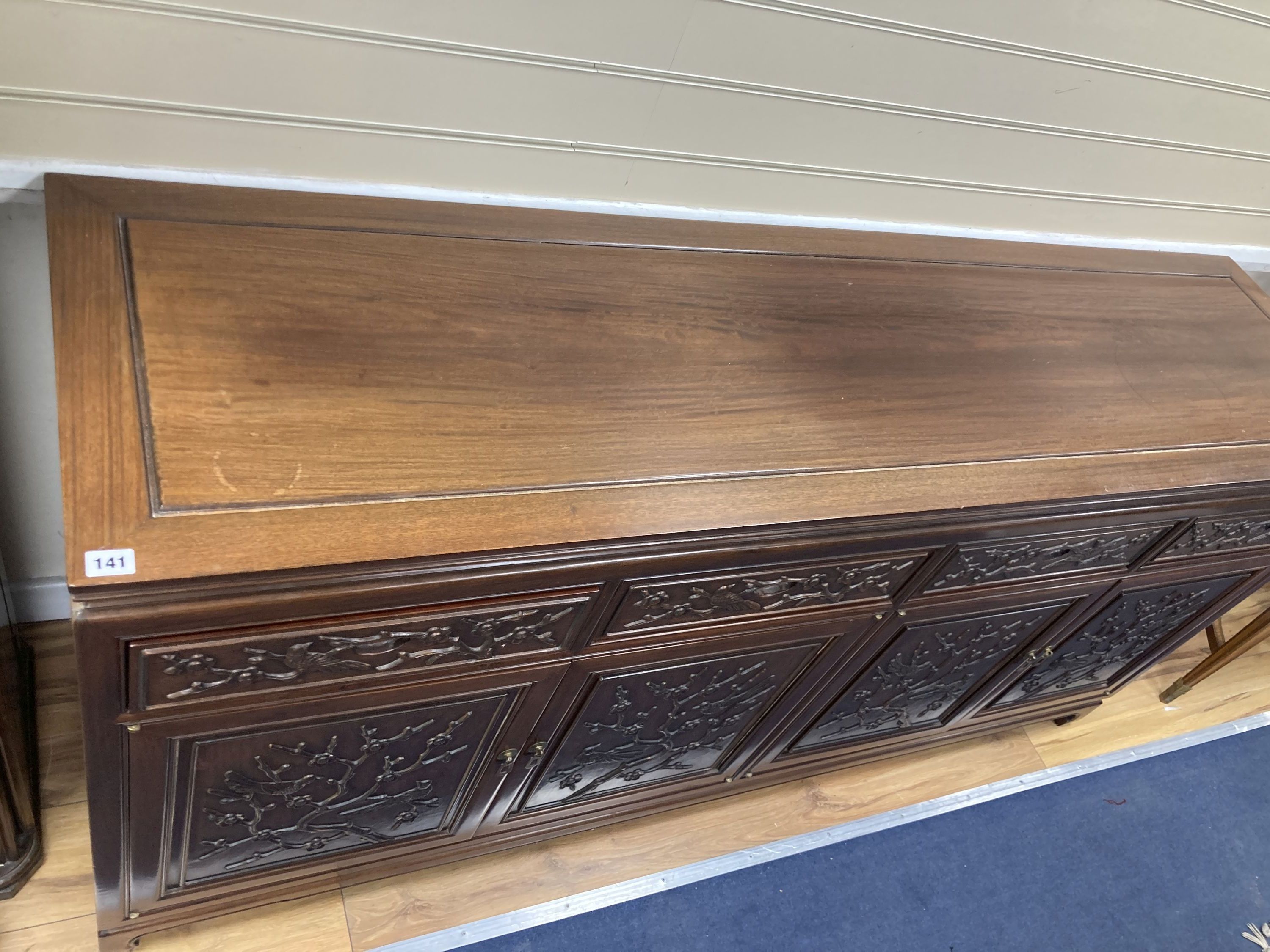 A 20th century Chinese carved hardwood dining room suite comprising sideboard fitted with four drawers above four carved panelled cupbo